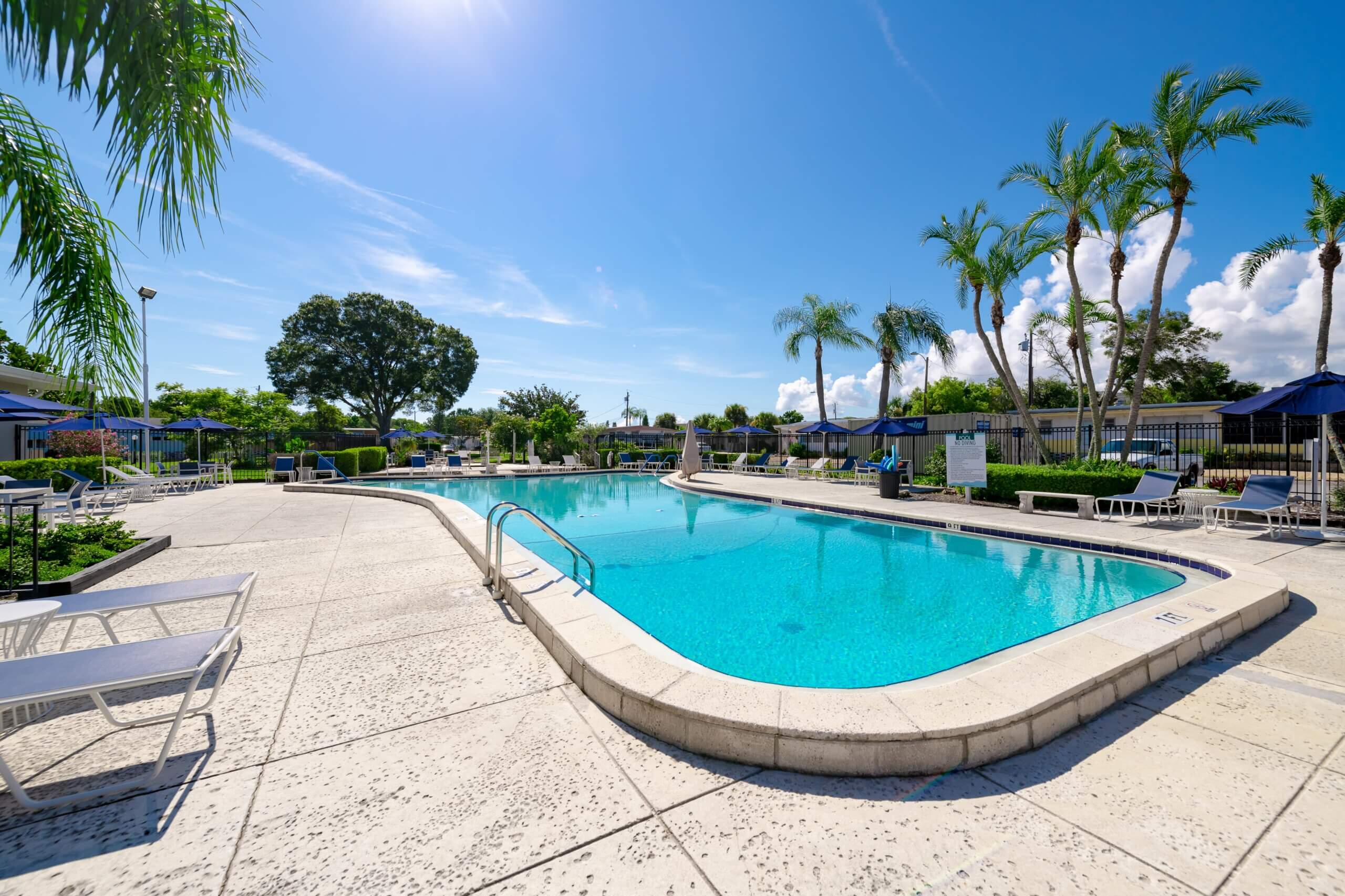 Fenced swimming pool area, with quarry-tile floors and outdoor blue sunbeds and chairs.
